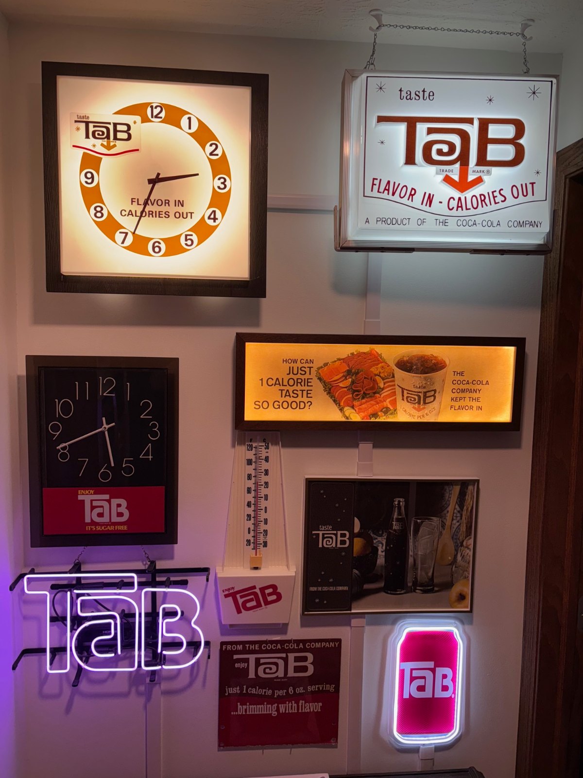 A collector’s wall of vintage illuminated TaB signs, clocks, and neon